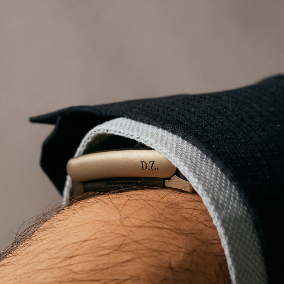 Close-up of a wrist wearing a bracelet with 'D.Z.' engraving, against a neutral background.