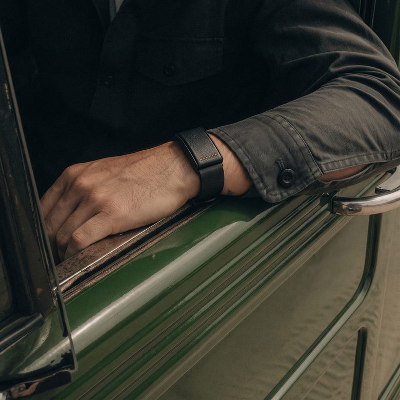 Ecoband 5.0 in Black & Orange worn with the arm resting on a vintage car window (black & orange)