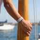 Ecoband 5.0 in Cloud worn on a sailing boat, hand on a wooden mast (cloud)