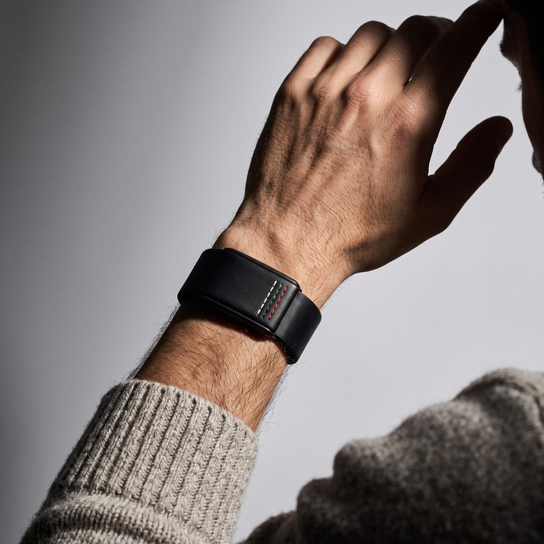 Ecoband 5.0 Roots in UAE Flag — black bio-leather WHOOP band with UAE flag stitching, worn with a knit sweater (uae flag)