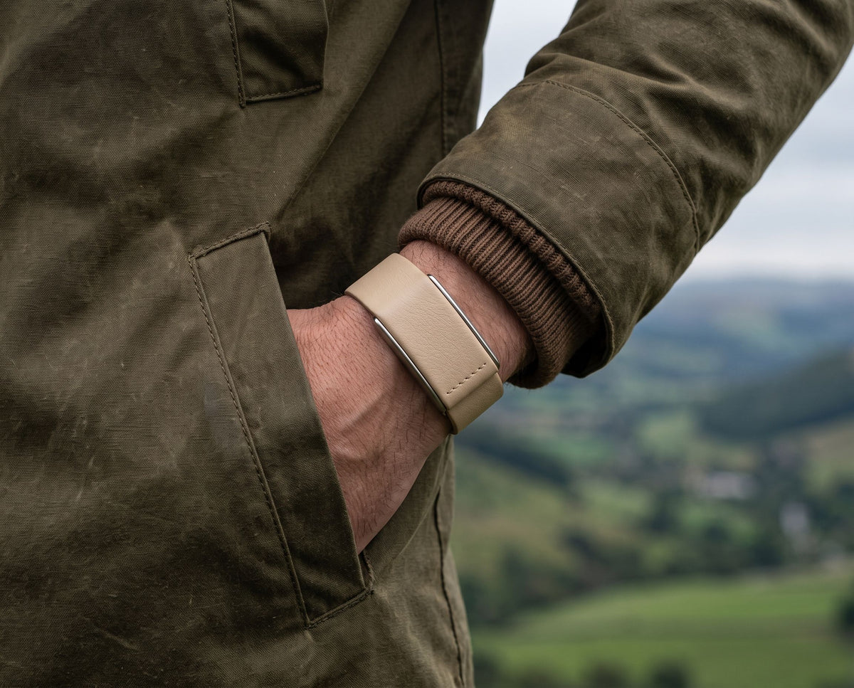 Ecoband 5.0 in Sand worn on a hillside walk, hand in jacket pocket (Sand)