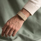 Ecoband 5.0 in Sand worn with a cream knit, resting on sage linen (Sand)