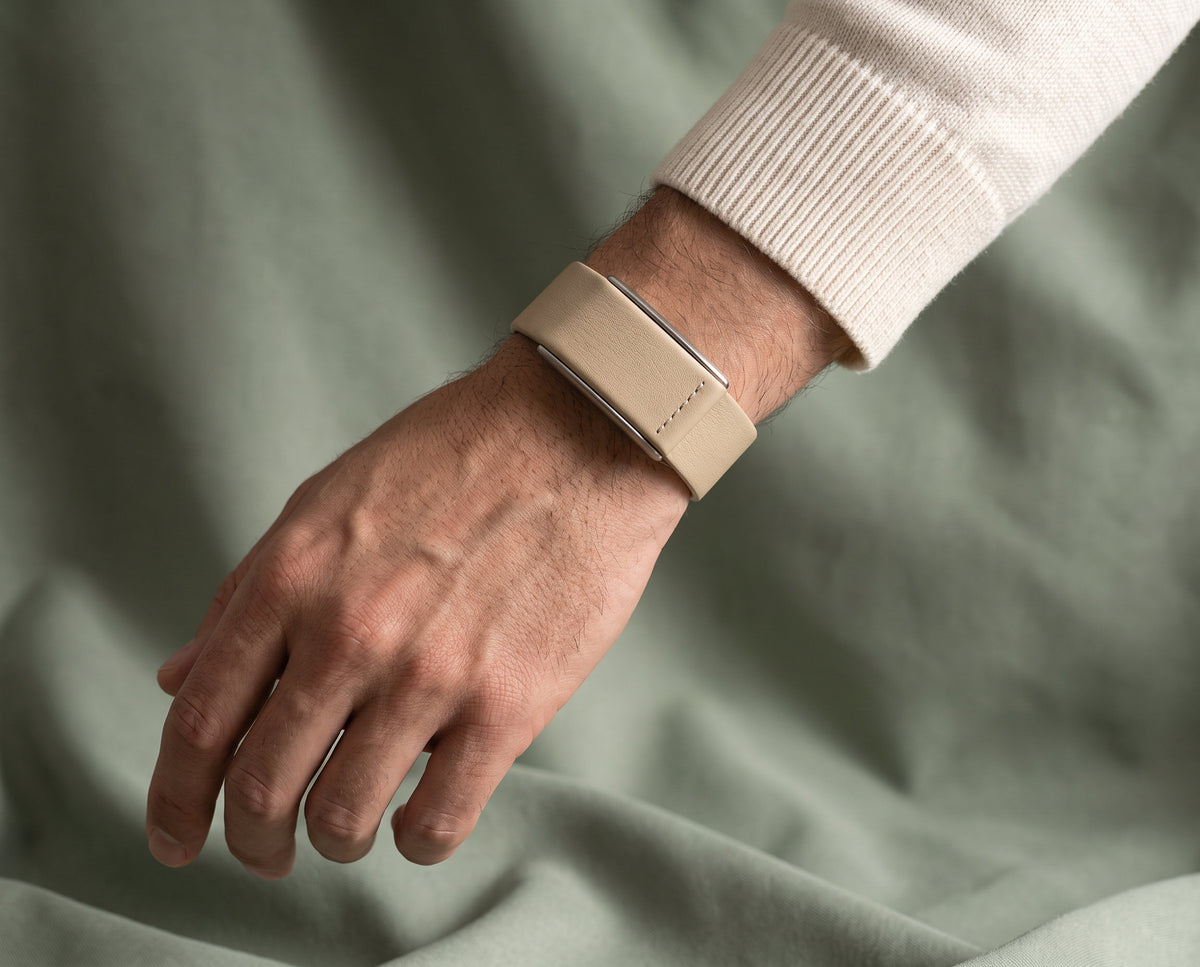 Ecoband 5.0 in Sand worn with a cream knit, resting on sage linen (Sand)