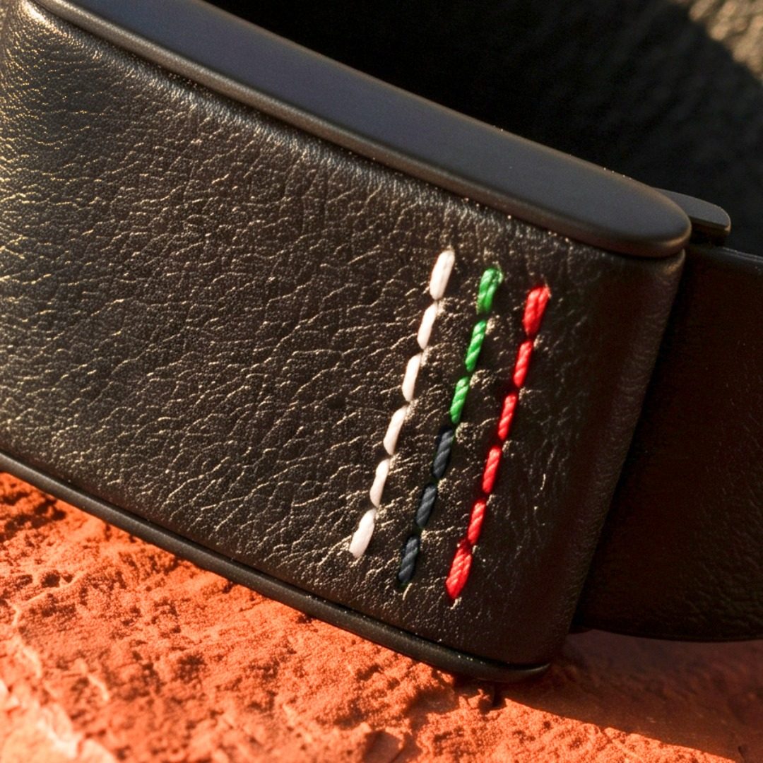 Ecoband 5.0 Roots in UAE Flag — black bio-leather WHOOP band with hand stitching in the UAE flag colours, on red rock (UAE Flag)