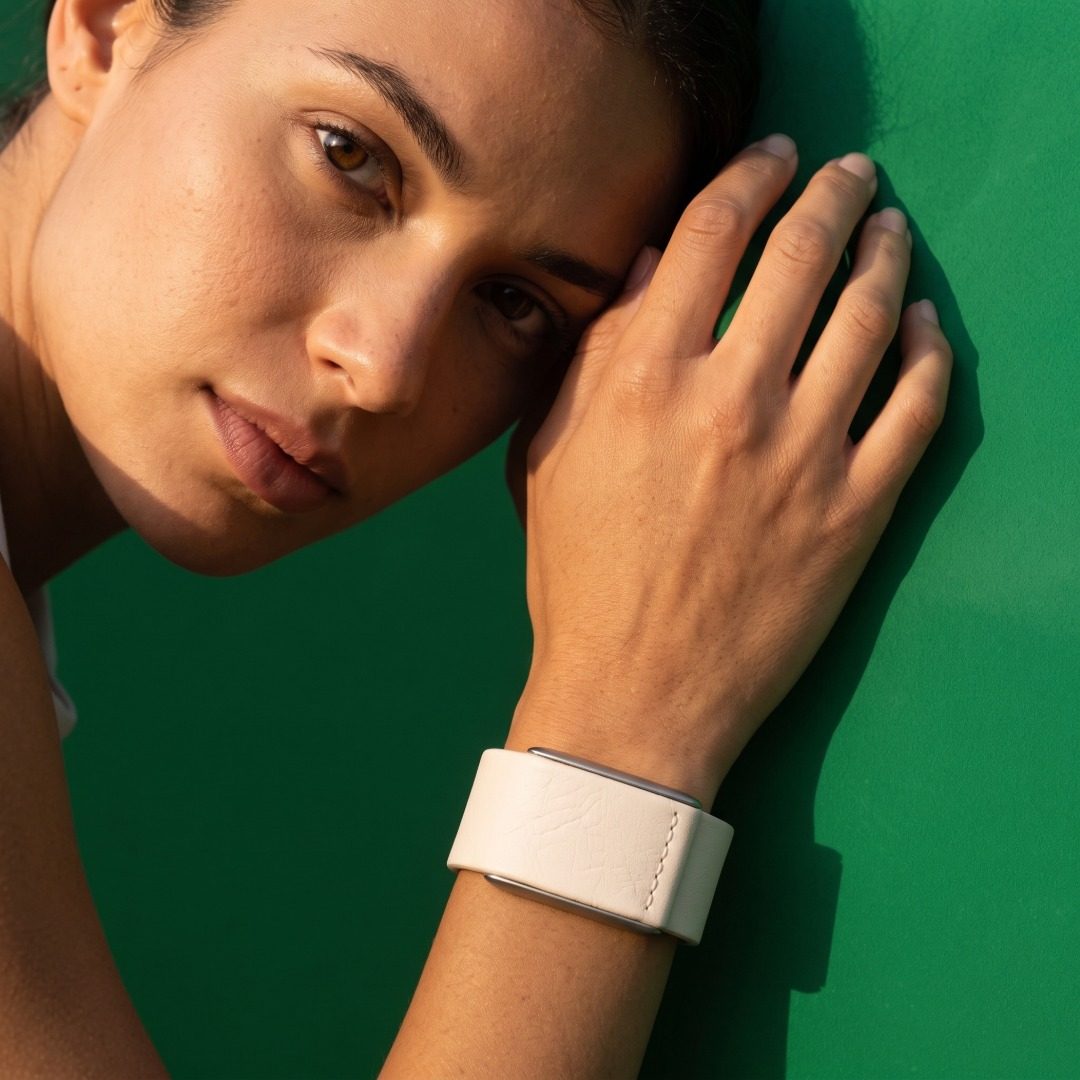 Ecoband 5.0 in Bianco worn on the wrist against a green wall (Bianco)